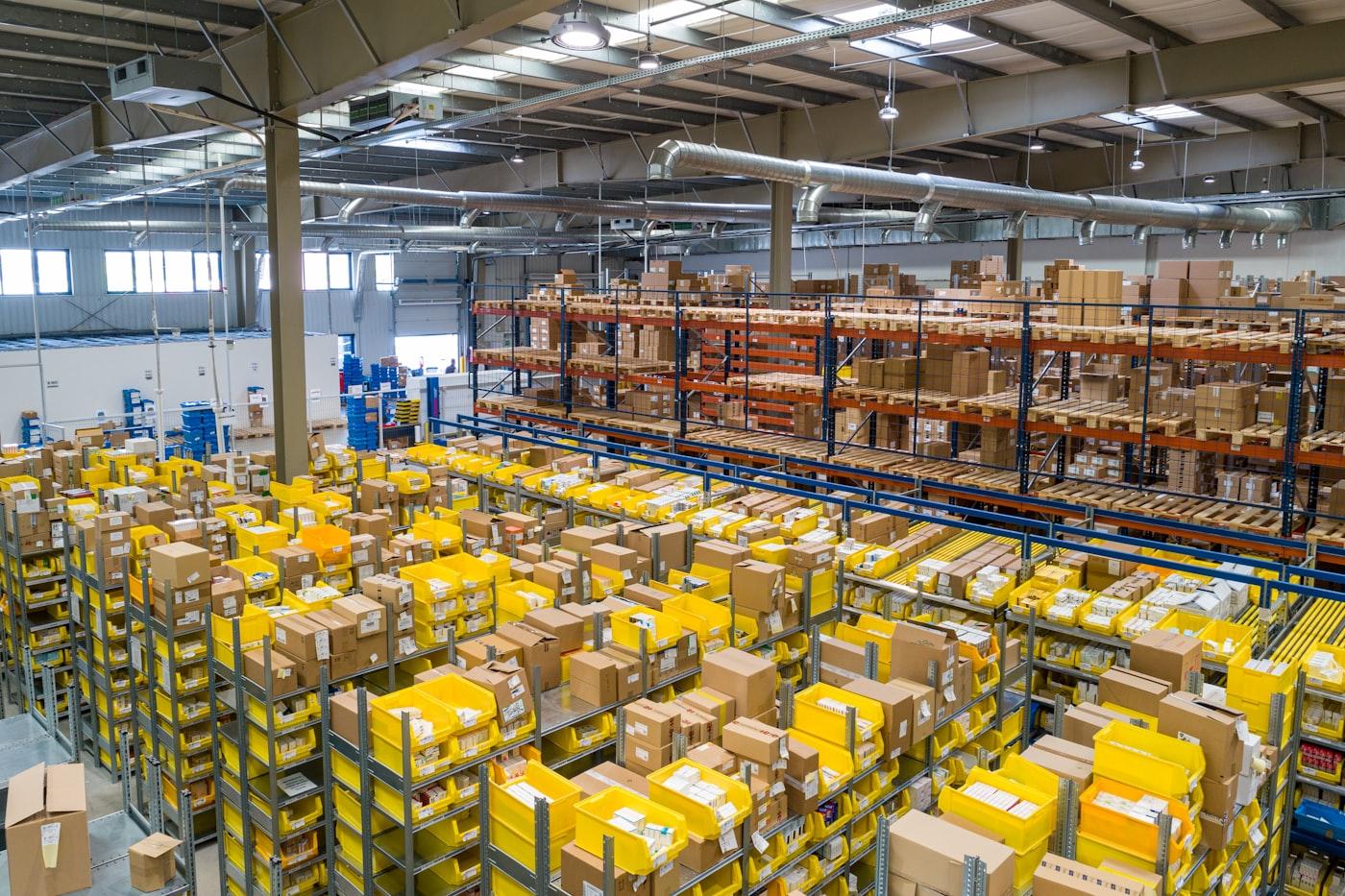 Entrepôt logistique avec bacs jaunes et cartons — univers industriel de l’emballage (photo d’illustration)